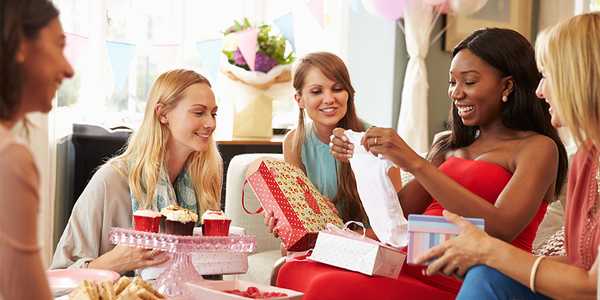 A group of women at a baby shower opening gifts.